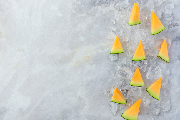 熟透的甜瓜放在一块块冰上，背景是灰色的大理石图片下载