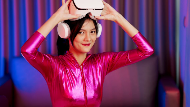 年轻的亚洲女性正在使用虚拟现实耳机。霓虹灯工作室肖像。虚拟现实、模拟、游戏和未来技术的概念。亚洲女人在卧室里玩游戏。图片下载