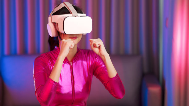年轻的亚洲女性正在使用虚拟现实耳机。霓虹灯工作室肖像。虚拟现实、模拟、游戏和未来技术的概念。亚洲女人在卧室里玩游戏。图片下载