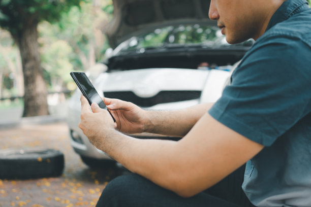亚洲男子在汽车抛锚后使用智能手机求救。对车辆发动机问题或事故的概念，以及专业机械师的紧急帮助图片下载