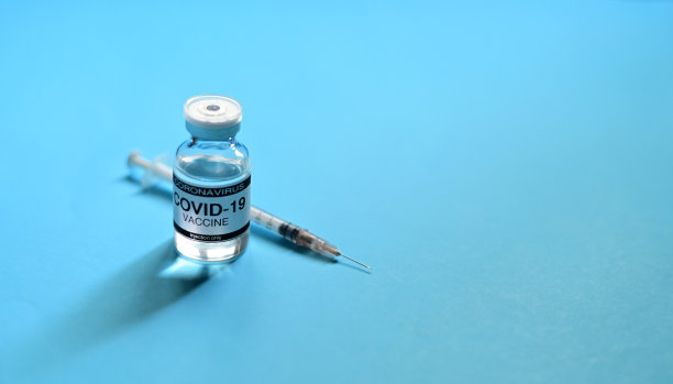 泰国新冠肺炎疫苗玻璃瓶和注射器，蓝色背景，蓝色表面。病毒在世界各地传播。有选择性的重点。图片下载