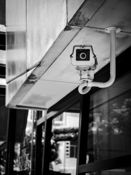 老式白色闭路电视摄像机悬挂在现代混凝土建筑上。图片下载