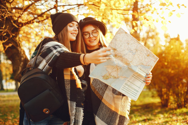 两个年轻的女孩在秋天的城市和公园里漫步图片下载