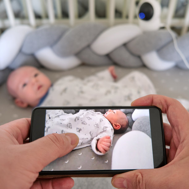 通过在线的家庭监控摄像头和手机上的互联网监控婴儿床上的新生儿图片下载