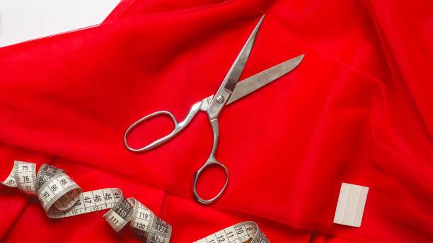 裁剪的概念。缝纫和针线活用的配件。红色布料和卷尺。图片下载