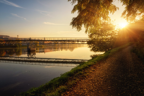 斯洛文尼亚马里博尔市，日出时德拉瓦河上的人行桥和人行道的风景。神奇的阳光明媚的风景图片下载