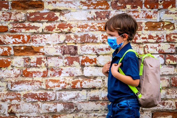 一名严肃的小学生戴着防护口罩走回学校图片下载