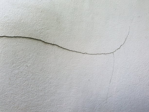 混凝土墙壁上抹着灰泥，漆成白色，有明显的裂缝。施工砂浆的缺陷。图片下载