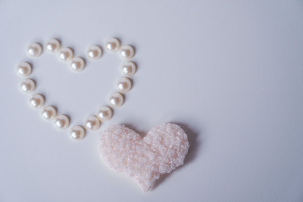 精致的米色绒毛心和珍珠在白色背景。爱的概念。情人节快乐。小女孩一岁生日贺卡。图片下载