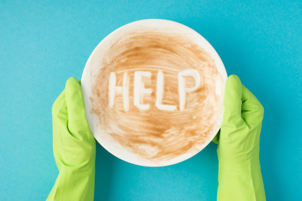 俯视图照片的手在绿色橡胶手套持有肮脏的盘子与题字帮助孤立的淡蓝色背景图片下载