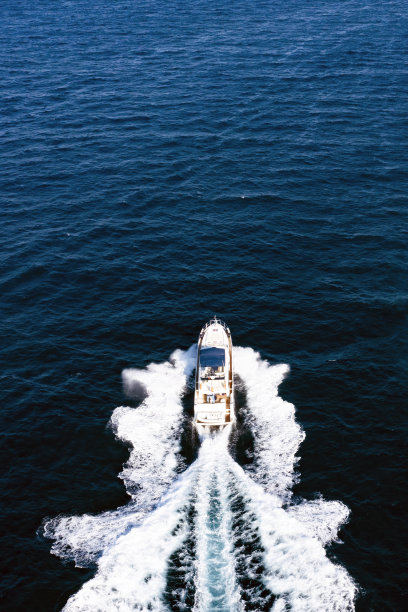 从上面看，令人惊叹的鸟瞰豪华游艇巡航在蓝色的水创造一个尾流。意大利撒丁岛的翡翠海岸。图片下载