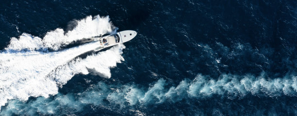 从上面看，令人惊叹的鸟瞰豪华游艇巡航在蓝色的水创造一个尾流。意大利撒丁岛的翡翠海岸。图片下载