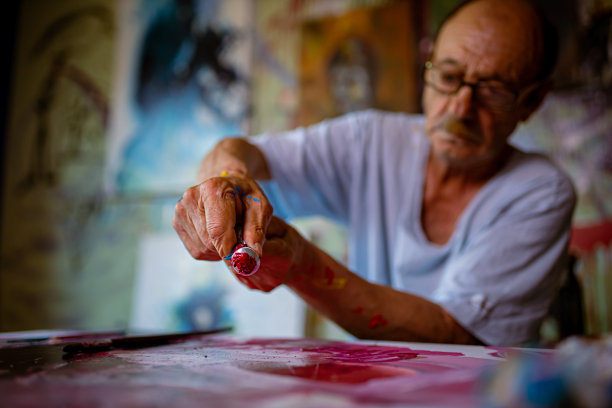 专业资深画家从管中挤出红色油彩图片下载