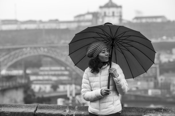 多云天气下，葡萄牙波尔图一位多文化妇女打着伞。黑白照片。图片下载