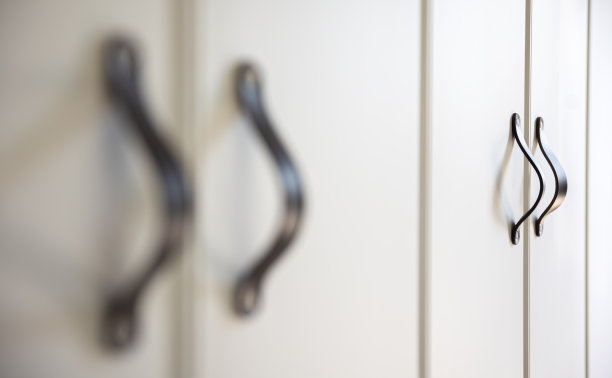 白色橱柜上黑色旋钮的特写。图片下载