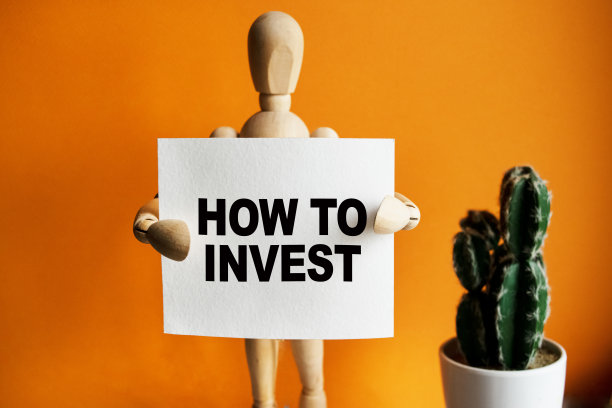 木头人手里拿着一块白色的牌子，上面写着“如何投资”。字母的内容具有商业概念和营销的含义。图片下载