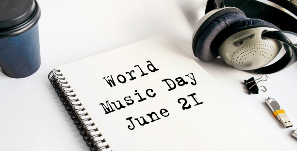 笔记本上的题词是世界音乐日。6月21日。安静的工作场所，有咖啡、耳机和笔记本。一个放松的时刻，与放松的音乐断开联系。从以上观点。图片下载