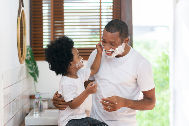 快乐的黑人单身父亲和小儿子在家里的浴室里玩剃须泡沫图片下载