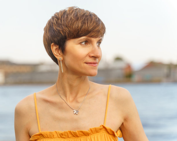 中年妇女站在城市的河堤边，享受着夏天图片下载