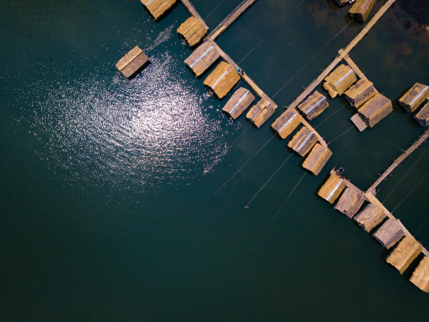 风景秀丽的竹筏村舍在湖上与阳光反射在水面。图片下载