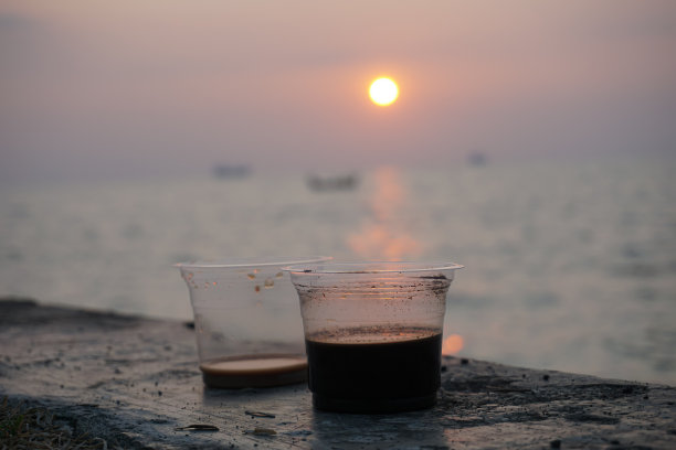 两杯咖啡，日出在海上的背景图片下载