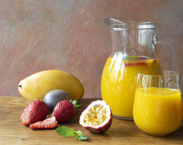 水壶和玻璃杯与热带清新的鸡尾酒与芒果，草莓，芒果和百香果在咖啡馆的木桌复制空间和特写图片下载