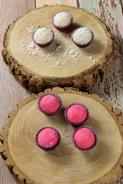 草莓Brigadeiros (Bicho de Pe)在树干菜。背景是切碎椰子的椰子旅(垂直照片)。图片下载