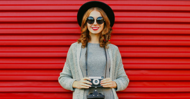 年轻的女摄影师的肖像与旧胶卷相机在红色的背景图片下载