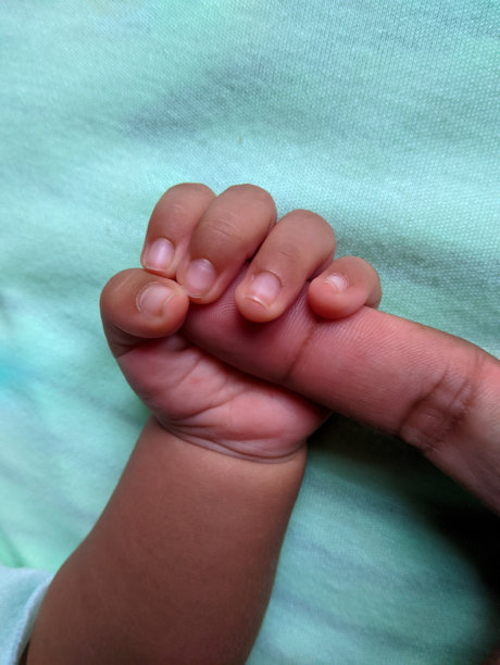 新生婴儿的手牵着父亲的食指。蓝绿色的孤立。父亲对孩子的爱图片下载