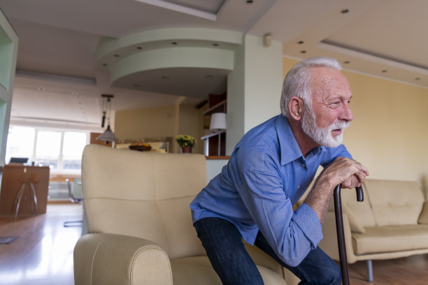 拄着拐杖的残疾老人坐在家里，背部疼痛难忍，试图站起来。图片下载