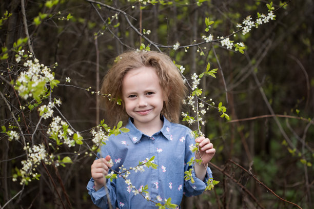 一个可爱的白人小女孩站在一棵盛开的樱桃树下图片下载