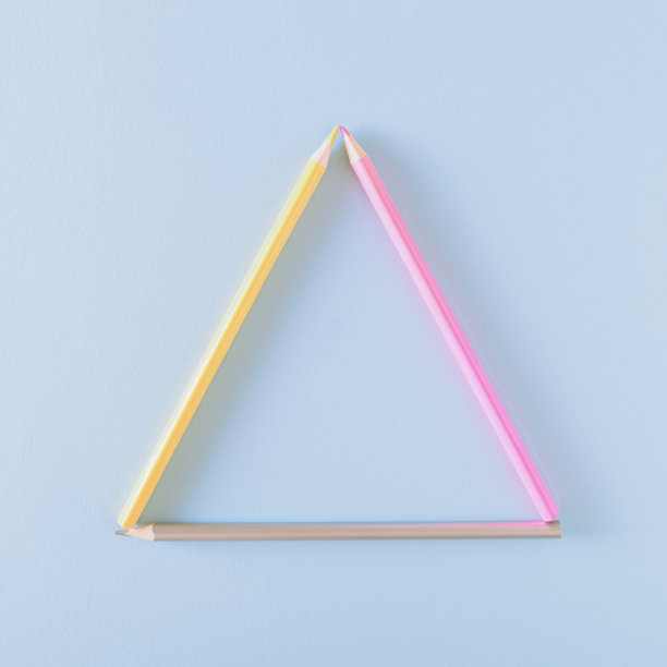 粉红色、黄色和灰色的铅笔排列在蓝色背景的三角形中。回到学校的概念。图片下载