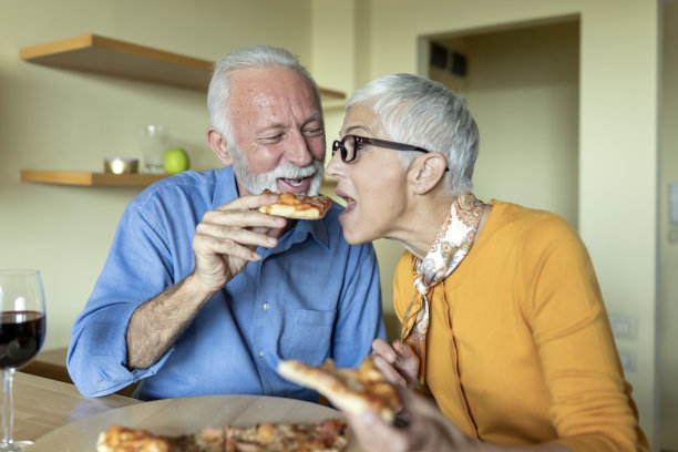 一个老男人给他可爱的妻子一块披萨。图片下载