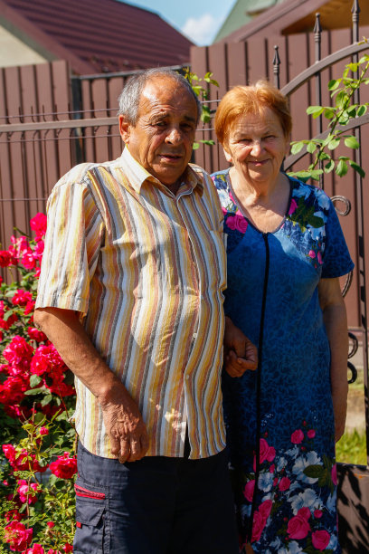 垂直整体肖像老年夫妇微笑在夏天的日子。幸福的老夫妻坐在花圃的背景上。六七十年代的男女。爱与家庭观念图片下载