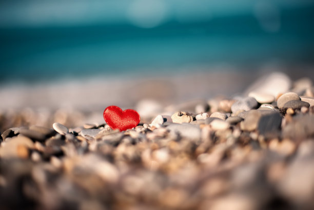 在海边模糊的背景上，石头上的红心。爱的象征图片下载