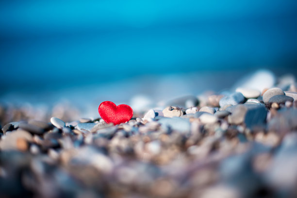 在海边模糊的背景上，石头上的红心。爱的象征图片下载