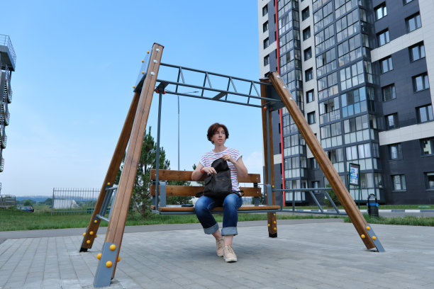 一个女人坐在摇摆的长凳上，打开背包图片下载