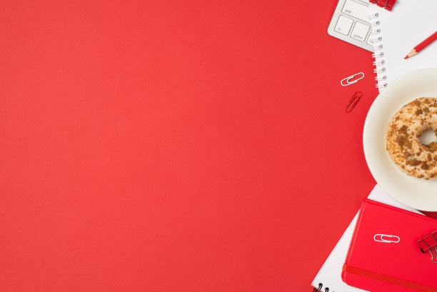 顶视图照片的工作场所键盘剪辑红色铅笔红色规划者和盘子装饰釉面甜甜圈孤立的红色背景与copyspace图片下载