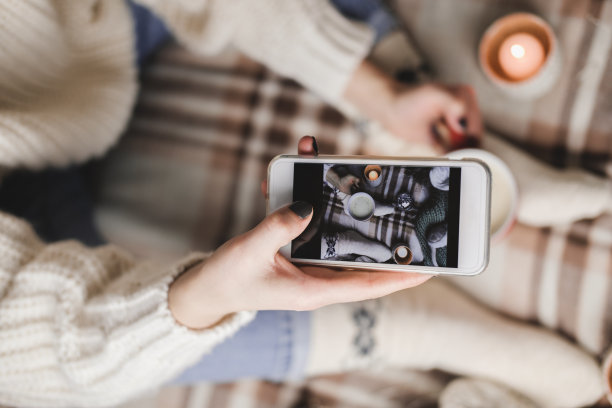 女性手拿智能手机在社交网络上拍新年或圣诞节的公寓照片。为假期做准备，创造内容。带棉花糖的可可杯图片下载