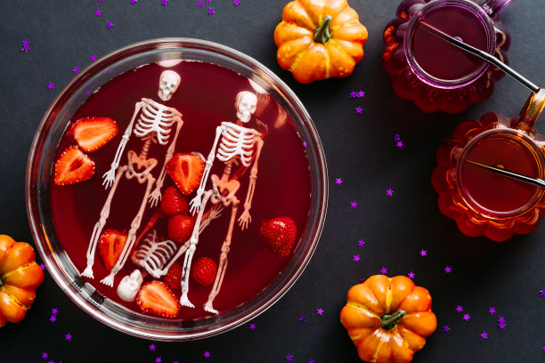 万圣节概念快乐。碗与血，草莓，骷髅和鸡尾酒在黑暗的背景。万圣节晚会平铺构图。图片下载
