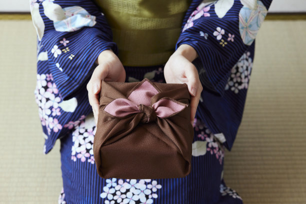 穿着日本服装的妇女手展示礼物图片下载
