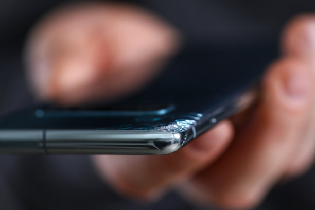 一名男子手持角落有裂缝的现代智能手机图片下载