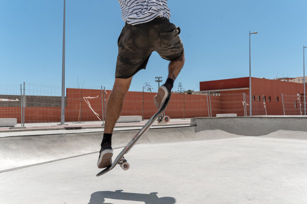 一个年轻人在滑板公园玩一种叫做“kickflip”的把戏。近距离图片下载