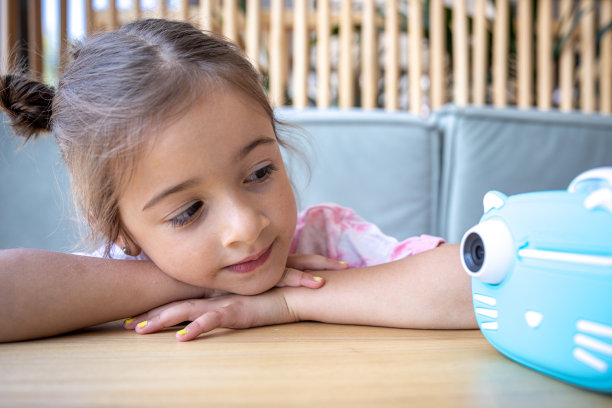 一个小女孩和一个用于即时打印照片的儿童相机。图片下载