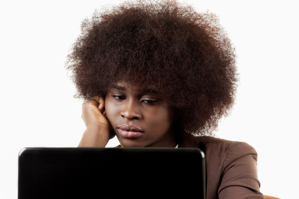 年轻的西班牙裔黑人商业主管，一头非洲式发型，无聊地看着白色背景下的笔记本电脑图片下载
