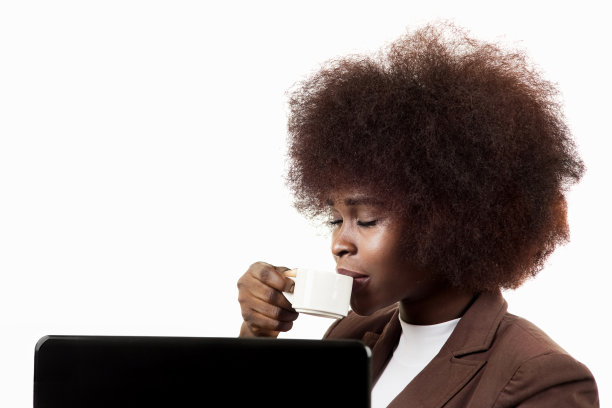 年轻的西班牙裔女性商业主管，一头非洲式的头发，微笑着喝着咖啡，在她的办公室的白色背景图片下载