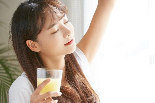 一个年轻的亚洲女人在喝果汁图片下载