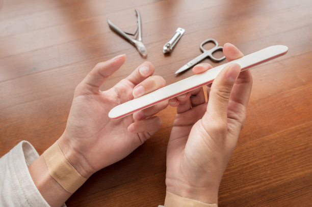 年轻的白种人美女坐在家里厨房的椅子上，忙着她的美容例行，整理和美容她的手指甲图片下载