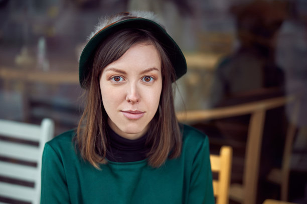 快乐的女人穿着绿色的衣服坐在城市的咖啡馆附近图片下载