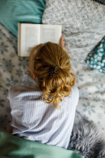 一个女人正躺在床上看书图片下载